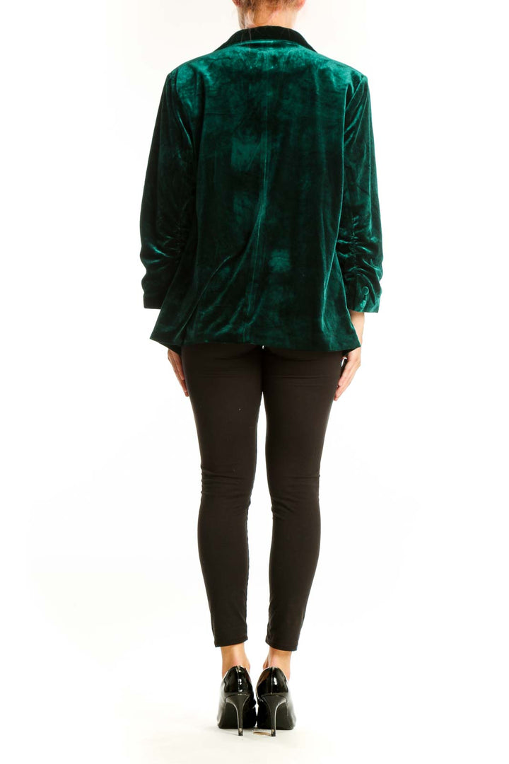 Side view of woman wearing emerald green velvet blazer jacket by Skies Are Blue