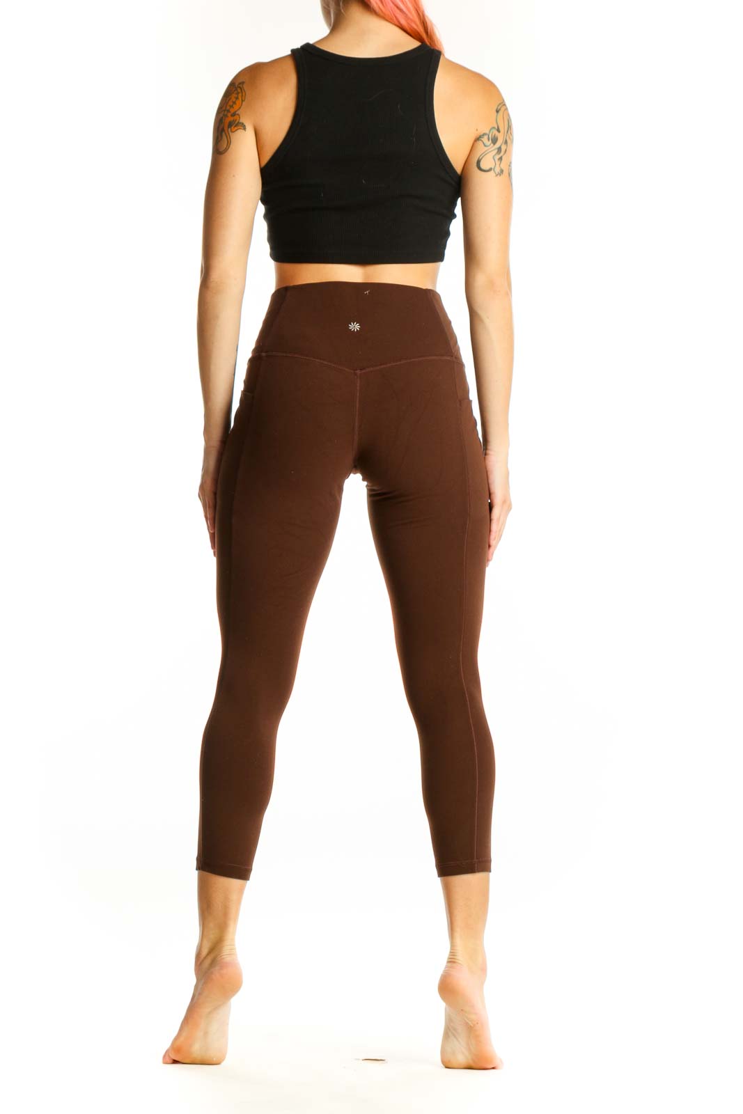 Side view of woman wearing brown Athleta capri leggings with black crop top
