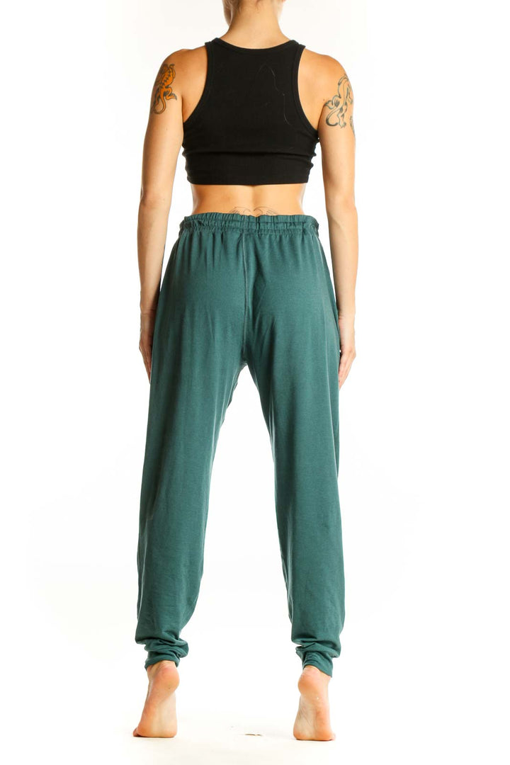 Side view of woman wearing green Vuori jogger pants with black crop top