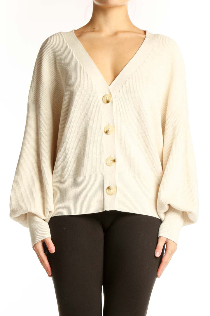 Cream ribbed button-front cardigan with puffed sleeves and gold buttons, worn with black pants