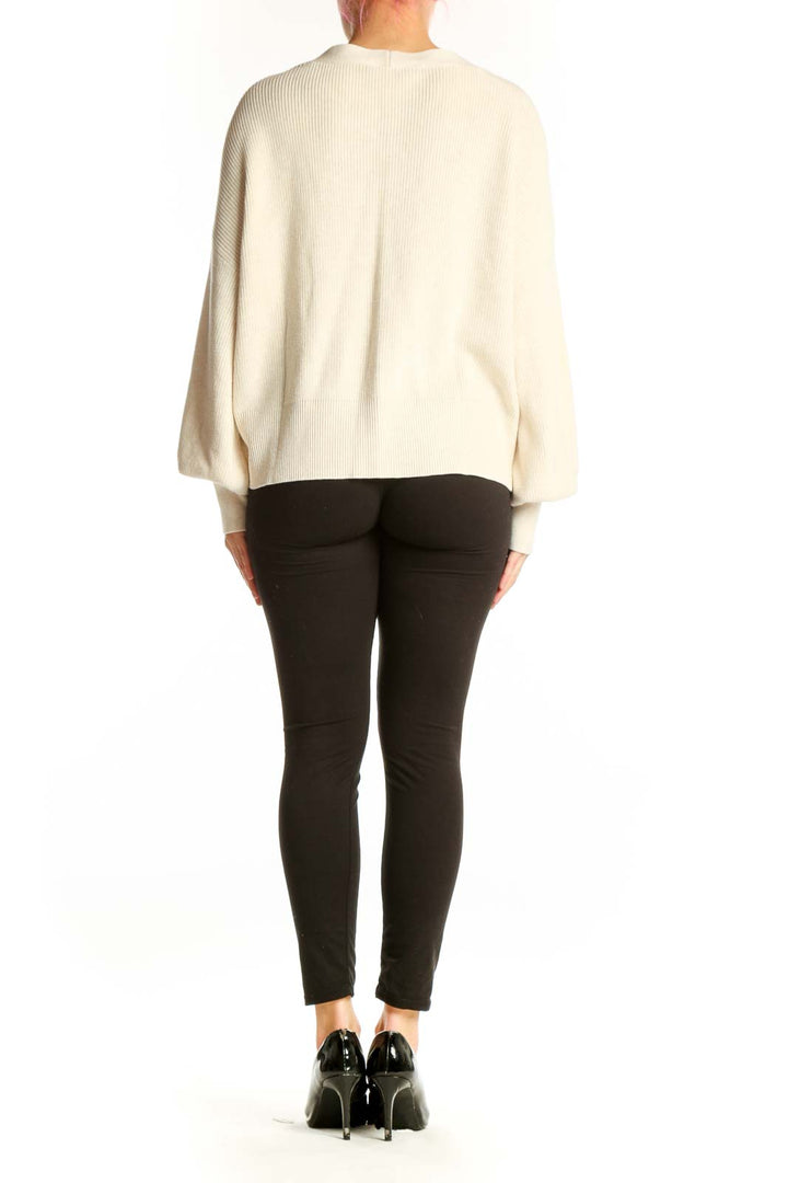Back view of cream ribbed cardigan showing button-front closure and voluminous puffed sleeves