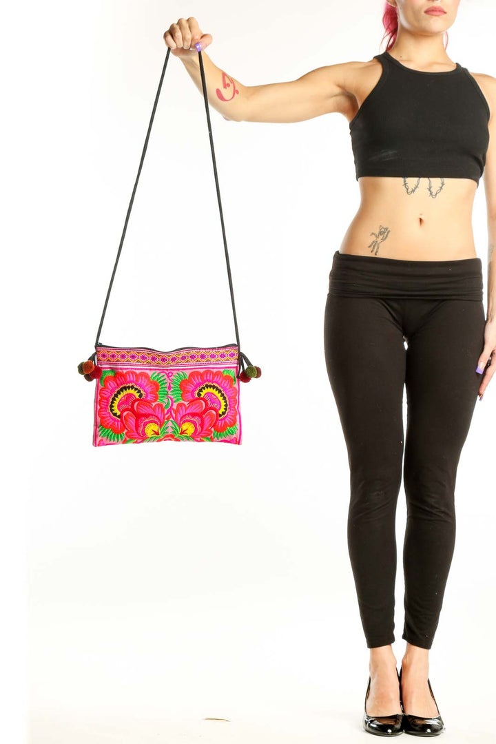 SilkRoll pink embroidered floral crossbody bag with vibrant red, yellow, and green botanical designs and pom-pom details