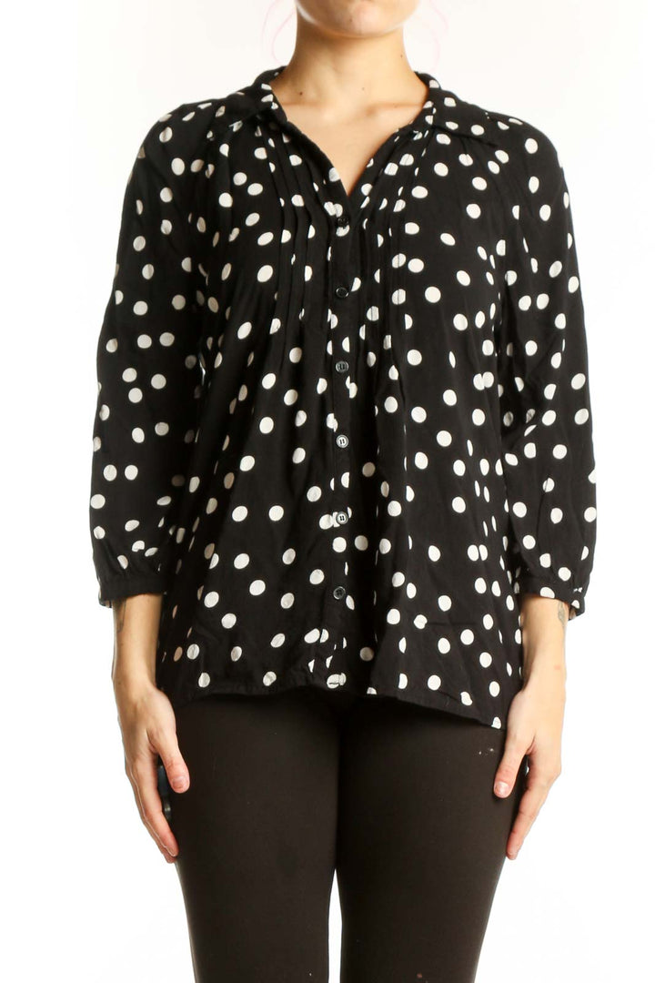 Black viscose top with white polka dots and button-up front, worn with black pants