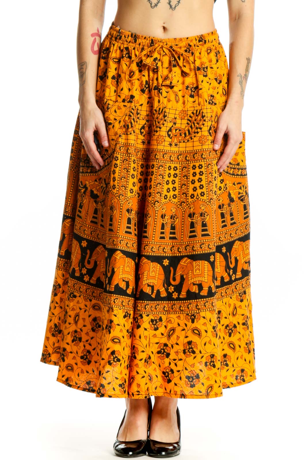 Front view of orange floral maxi skirt with elephant print band and geometric patterns, worn with black heels