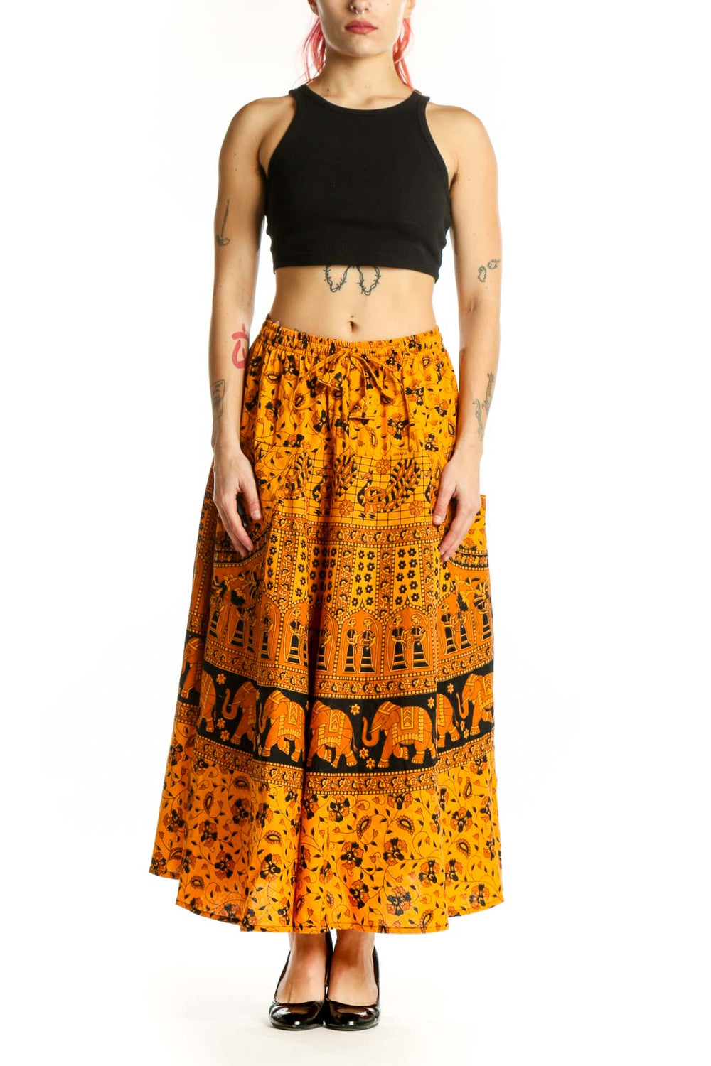 Front view of orange floral maxi skirt with elephant print band and geometric patterns, worn with black heels