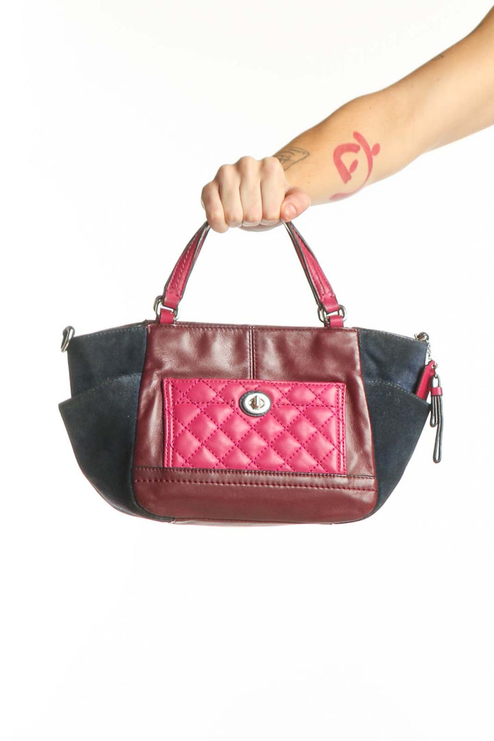 Burgundy and black quilted Coach satchel with dual handles and turnlock closure, held by hand