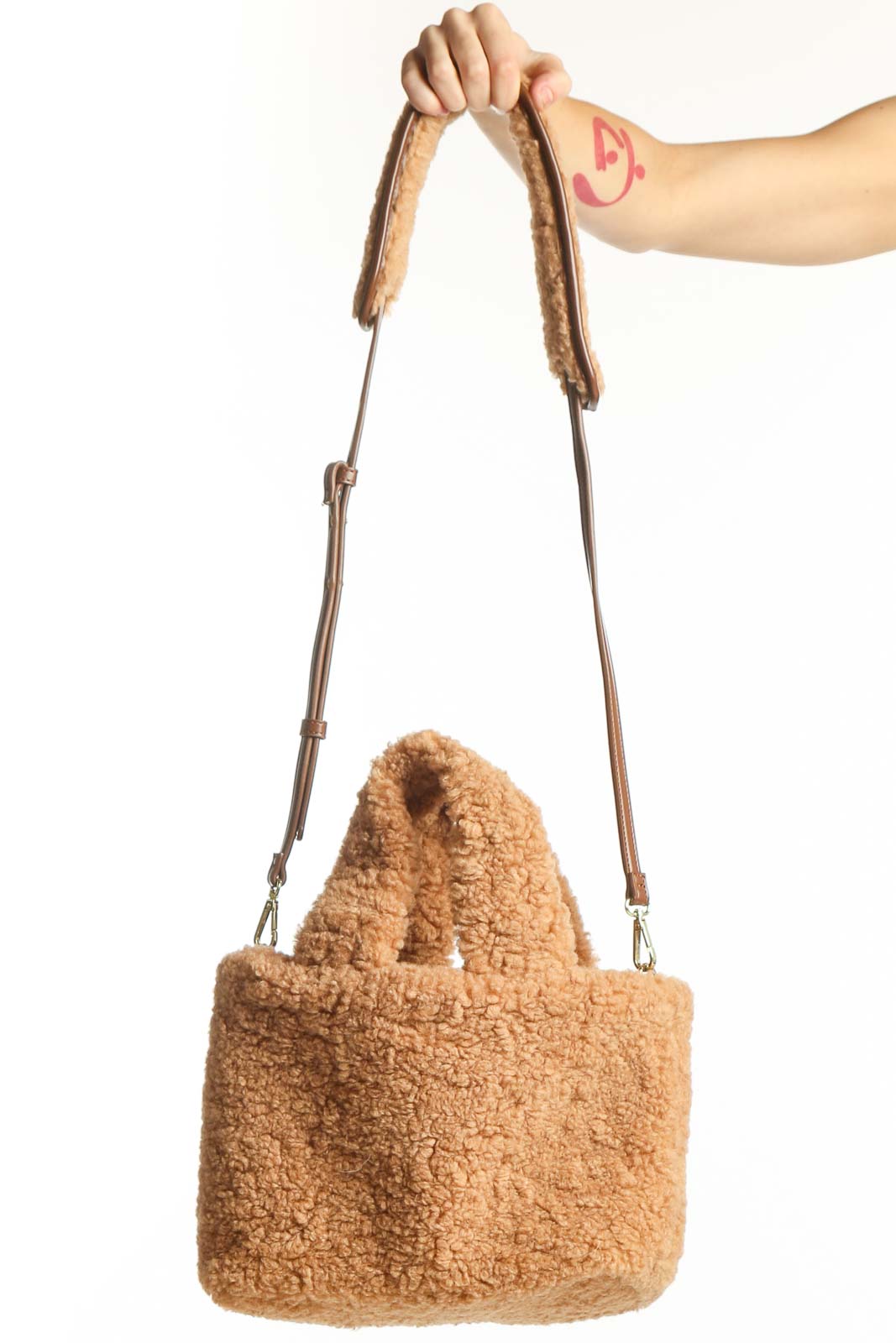 Beige teddy fleece satchel shoulder bag with leather straps held in hand, showing front view and texture