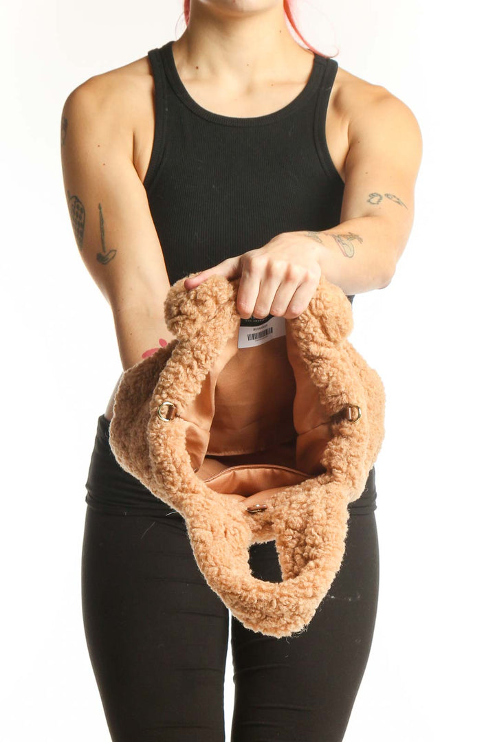 Back view of beige teddy fleece satchel bag worn as shoulder bag, displaying structured silhouette and strap adjustment