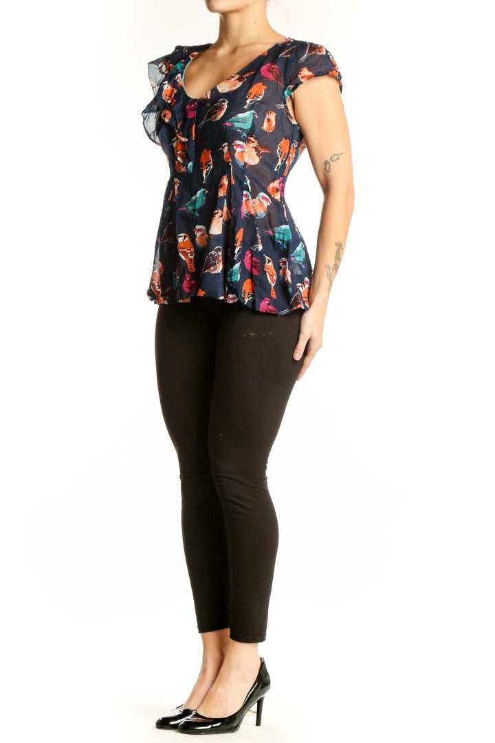 Navy floral cotton top with ruffle cap sleeves and peplum hem, featuring vibrant bird and botanical print