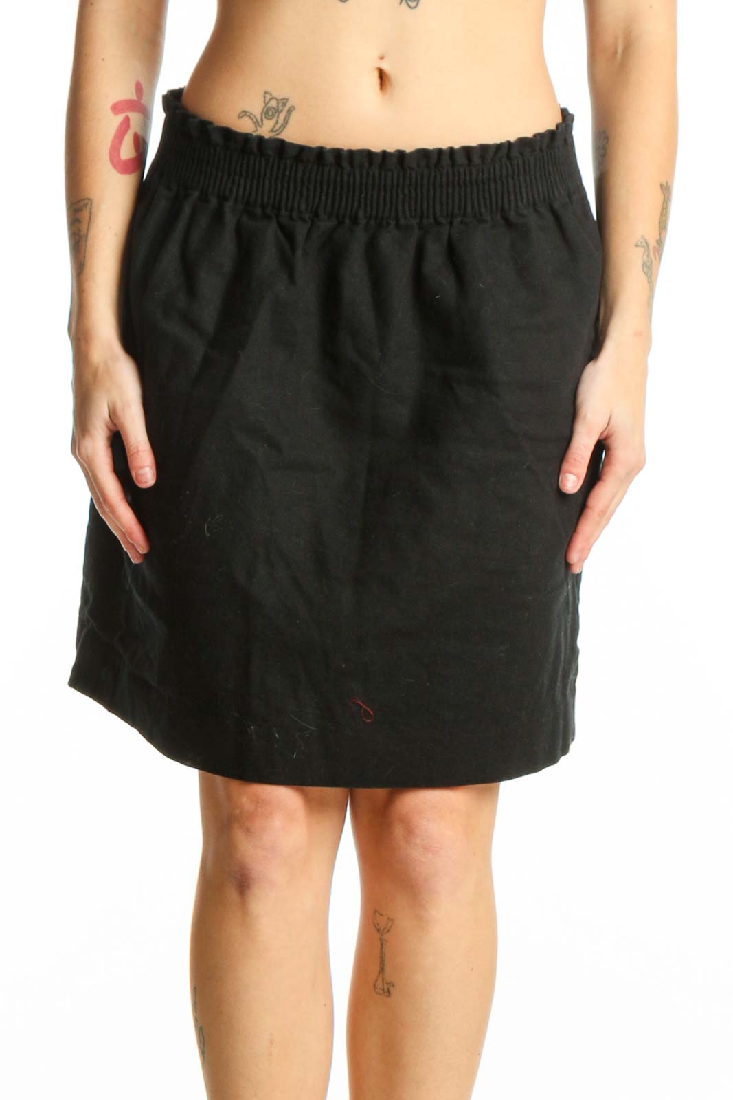 Black cotton-polyester mini skirt with elasticized waistband and side pockets, front view