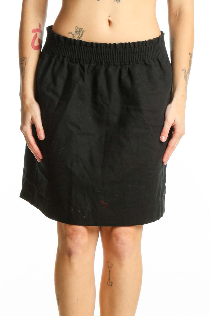 Black cotton-polyester mini skirt with elasticized waistband and side pockets, front view