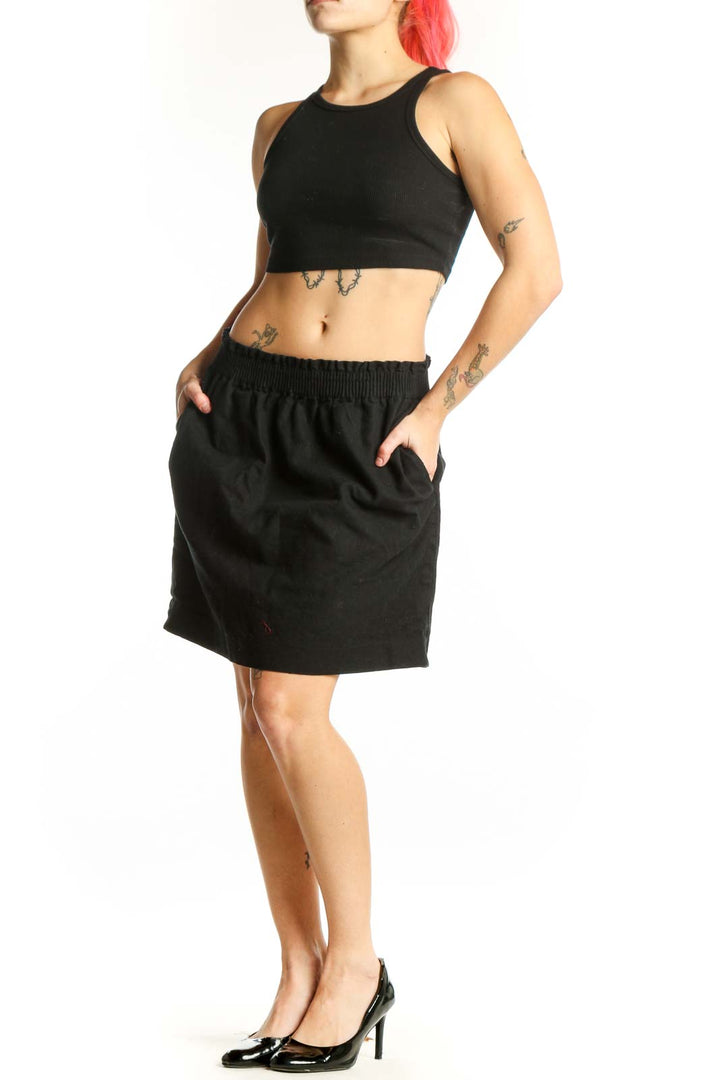 Black cotton-polyester mini skirt with elasticized waistband and side pockets, front view