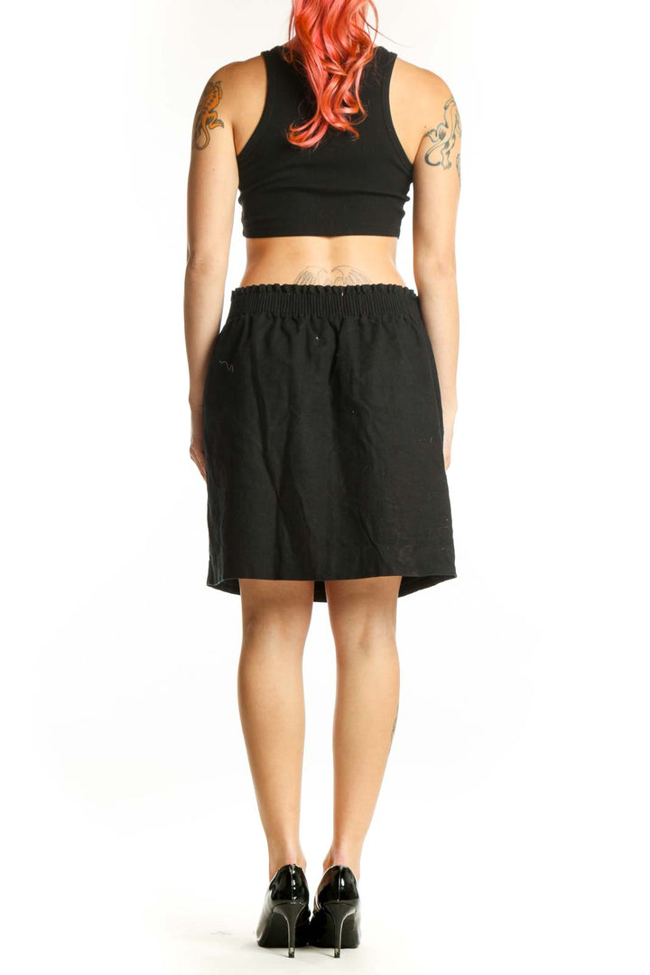 Black cotton-polyester mini skirt with elasticized waistband and side pockets, back view