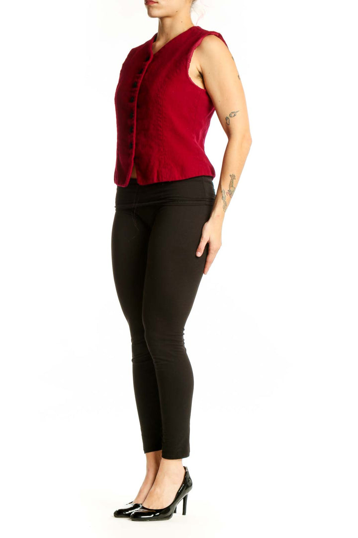 Red wool sleeveless button vest with V-neckline and black buttons, worn with black pants