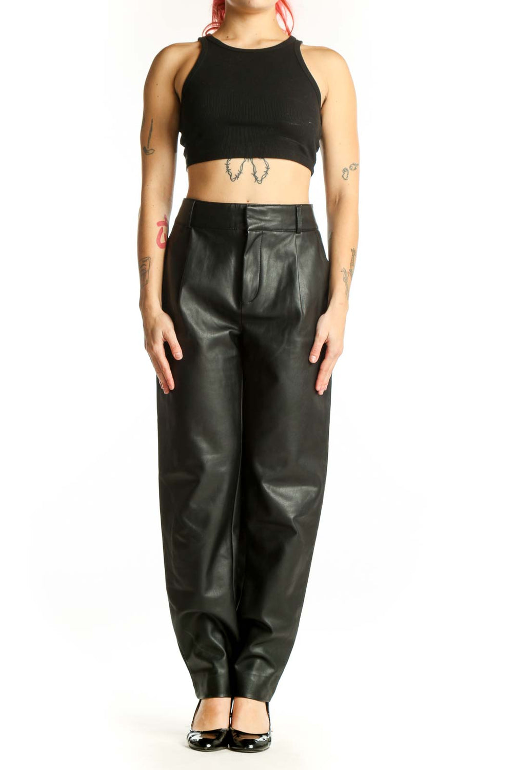 Black leather tapered pants with high waist and pleated front, worn with black platform heels