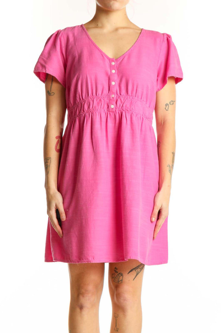 Pink short sleeve empire waist dress with button-front closure and ruching detail, front view