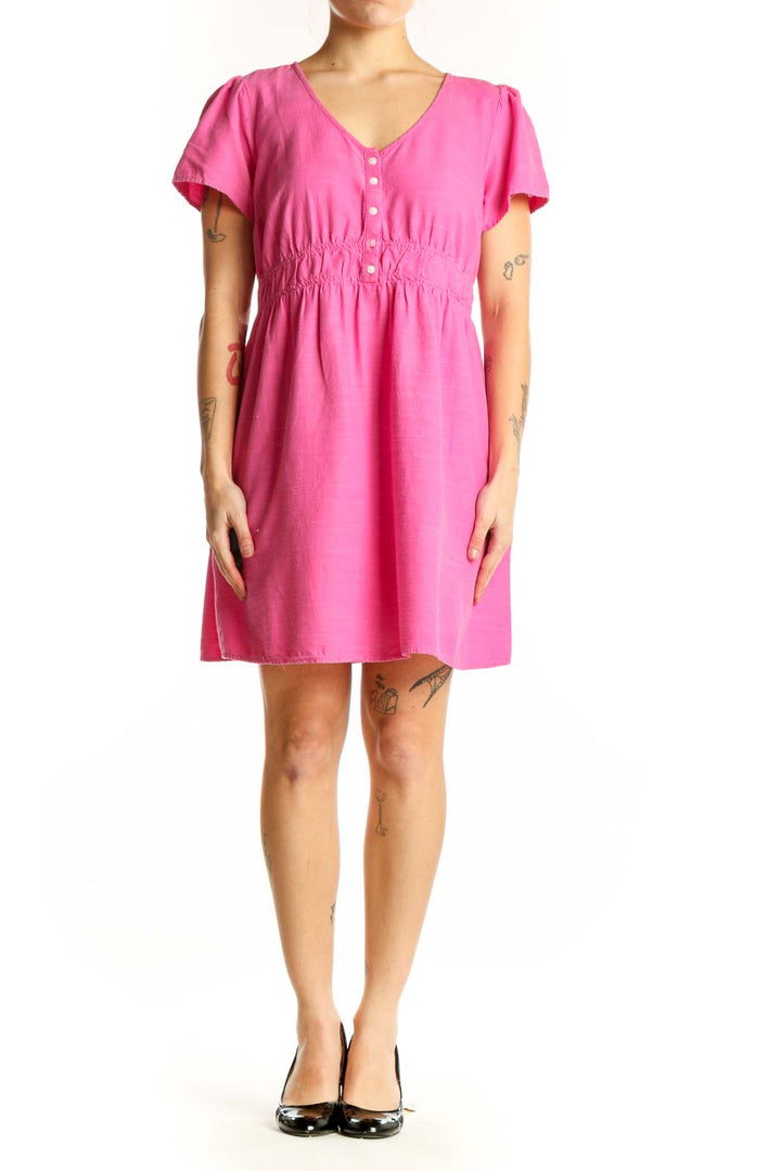 Pink short sleeve empire waist dress with button-front closure and ruching detail, front view