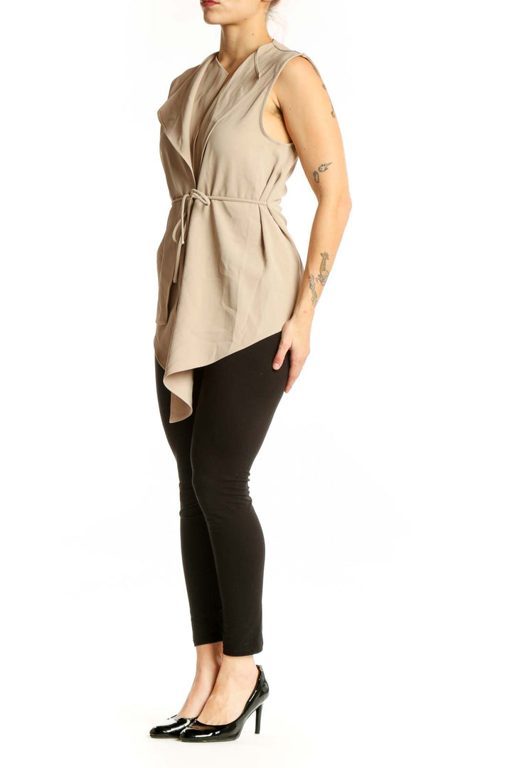 Beige sleeveless wrap vest top with tie waist and asymmetrical hem, front view on model