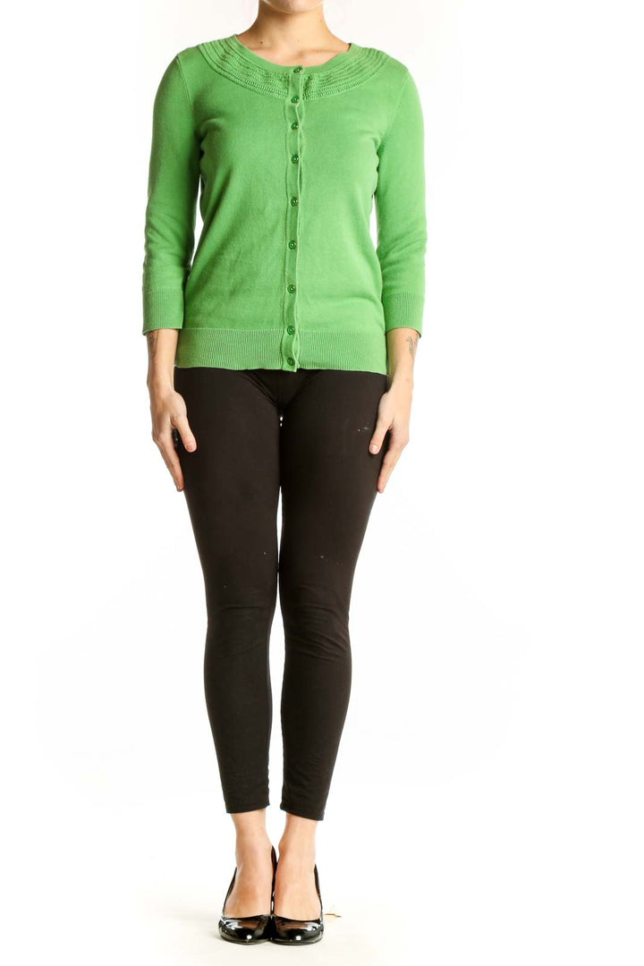 Green button-front cardigan with crew neckline and ribbed detailing, worn with black pants