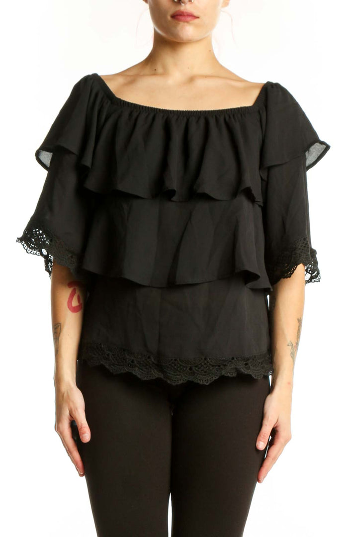 Black off-shoulder ruffled top with lace trim and layered tiers, front view on model