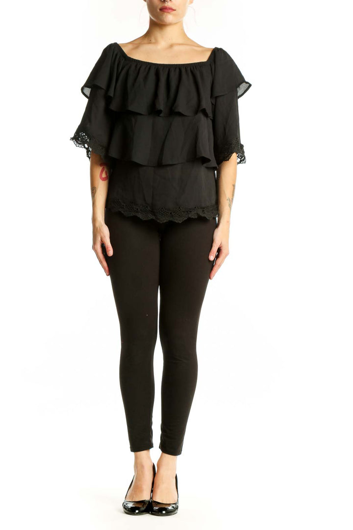 Black off-shoulder ruffled top with lace trim and layered tiers, front view on model