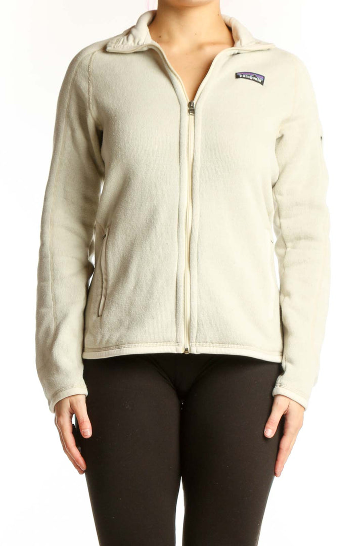 Front view of cream Patagonia fleece zip jacket with hood on woman wearing black leggings