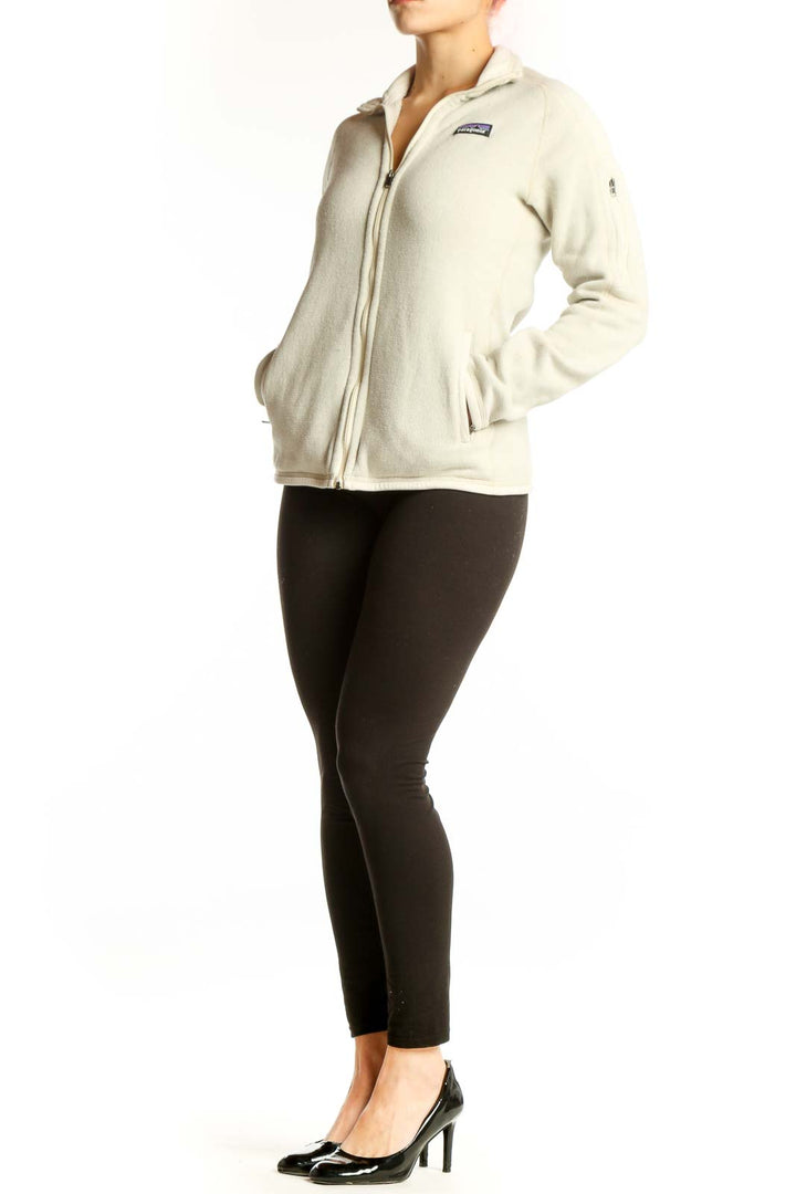 Front view of cream Patagonia fleece zip jacket with hood on woman wearing black leggings