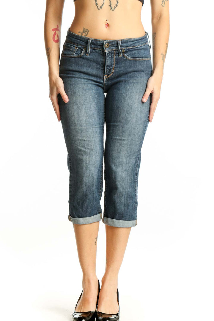 Front view of blue denim capri jeans with rolled cuffs and mid-rise fit on model