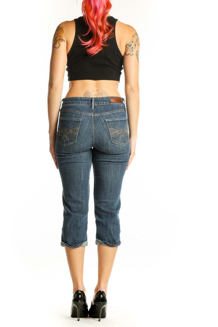 Back view of blue denim capri jeans showing five-pocket styling and rolled hem detail
