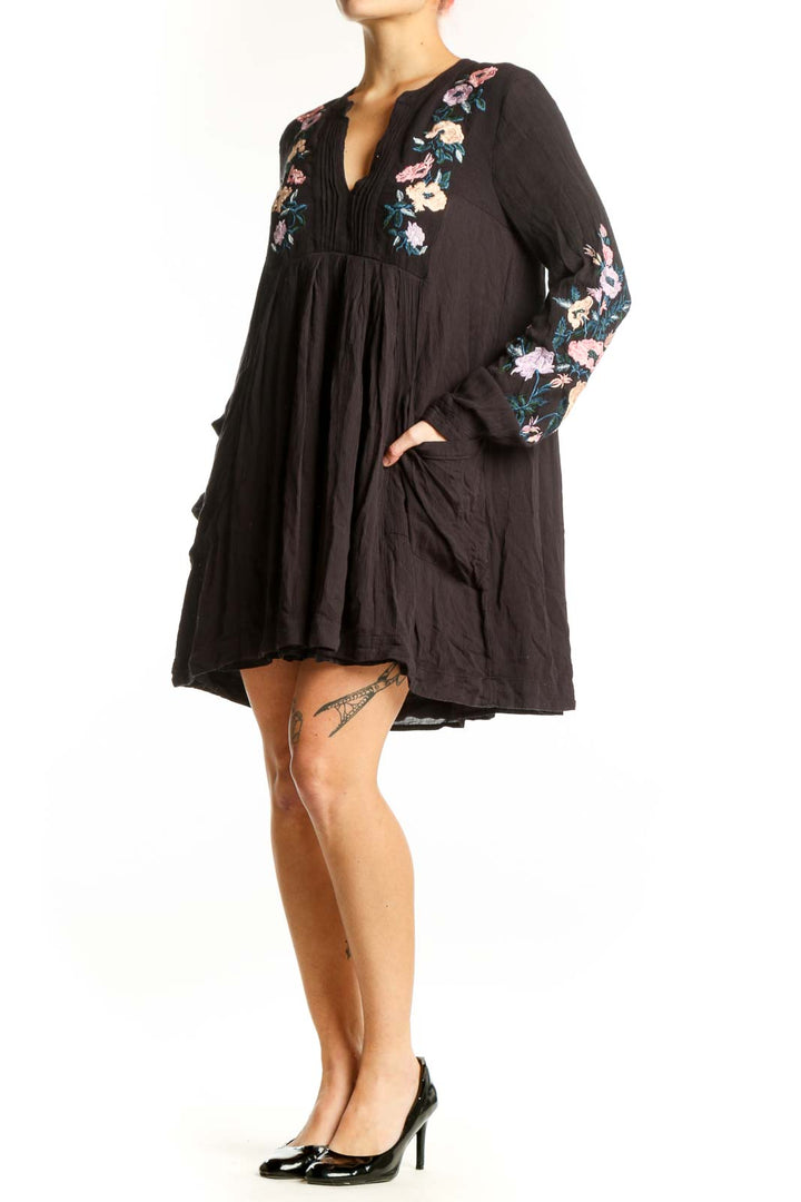 Black modal dress with floral embroidery on chest and sleeves, V-neckline with pleated detailing, flowing A-line silhouette