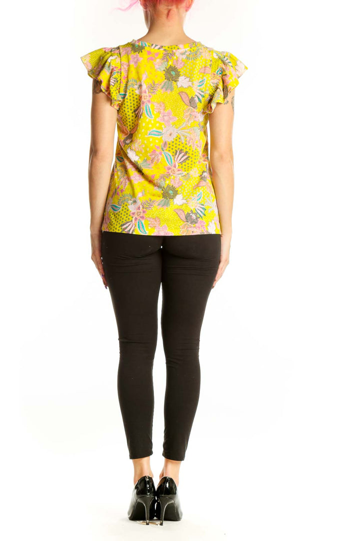 Yellow floral LOFT top with ruffle cap sleeves, back view on model wearing black pants