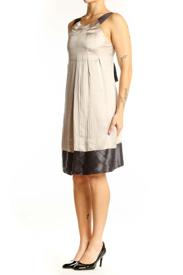 Front view of cream and black colorblock dress by Ted Baker London with pleated bodice and black shoulder trim