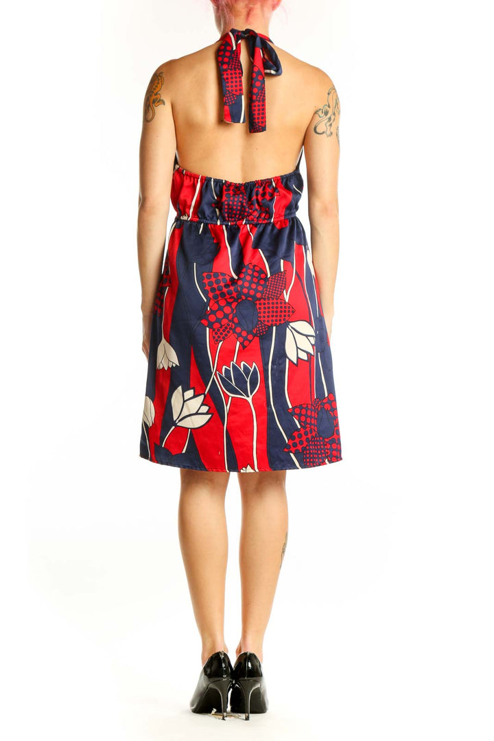 Back view of red and navy abstract ruffle midi dress showing sleeveless design and knee-length cut