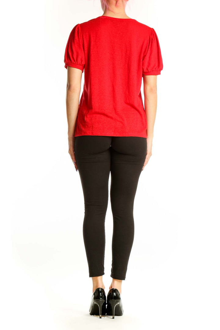 Red puff sleeve top by Banana Republic, back view on model wearing black pants