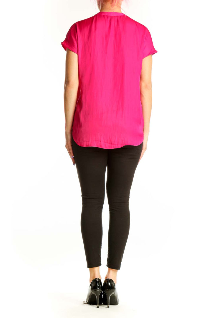 Back view of pink pleated V-neck top showing elegant draping and short sleeve design
