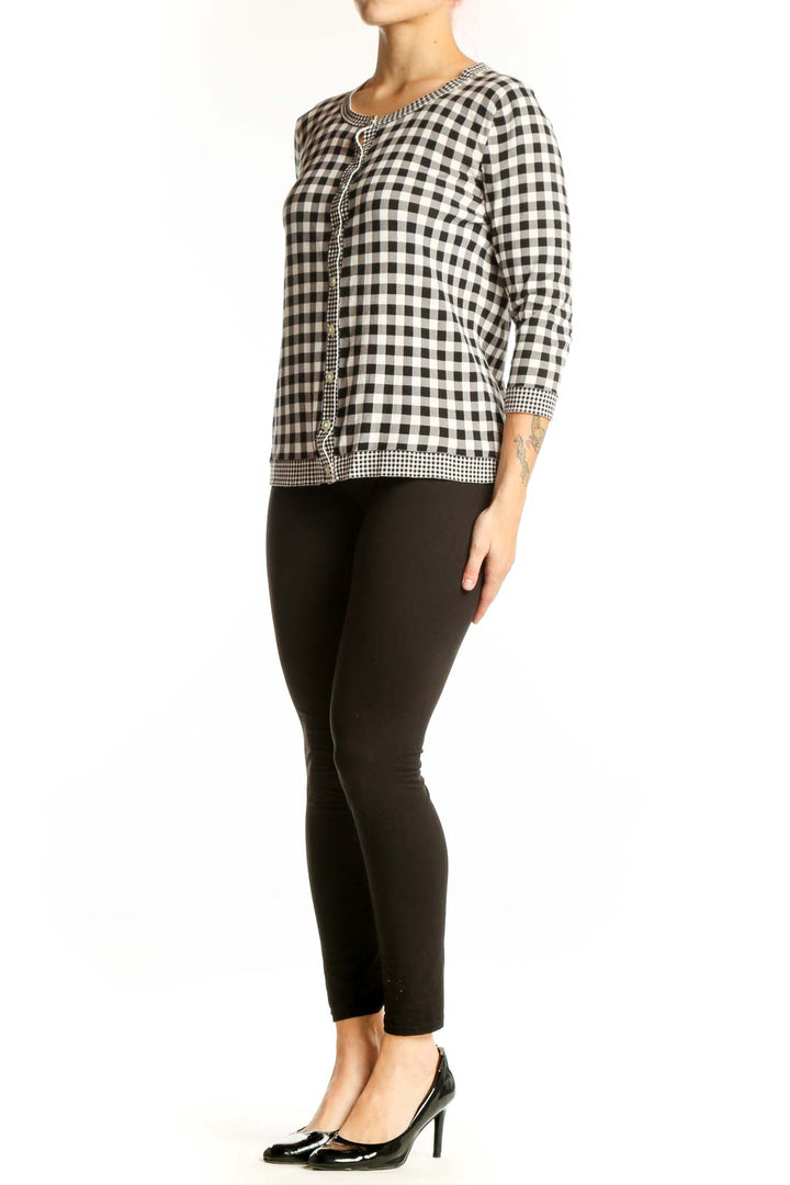 Black and white gingham knit cardigan with beaded trim and button-front closure, worn with black pants