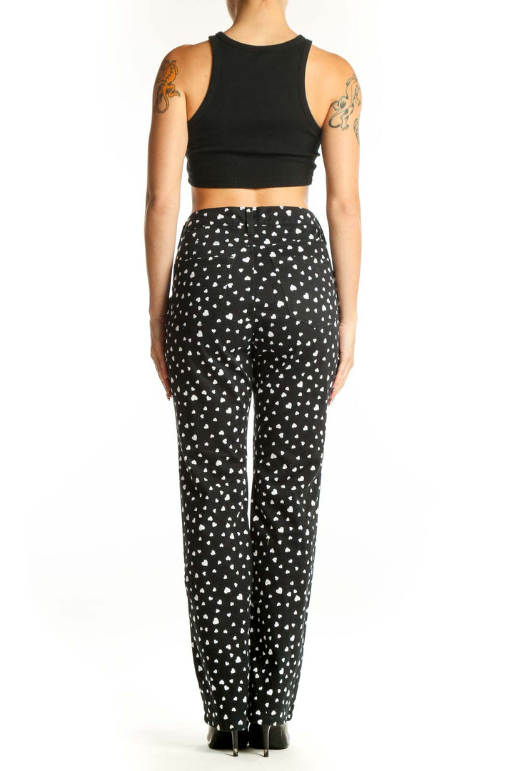 Side view of model wearing black heart-patterned pants with black crop top