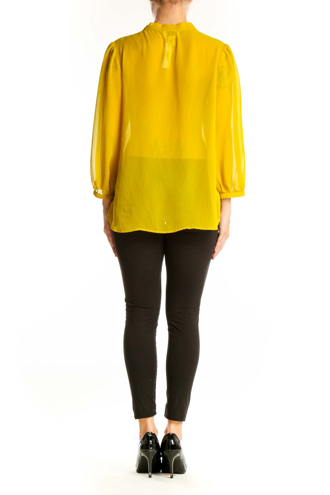Side view of yellow sheer tie-neck blouse from LOFT with black pants