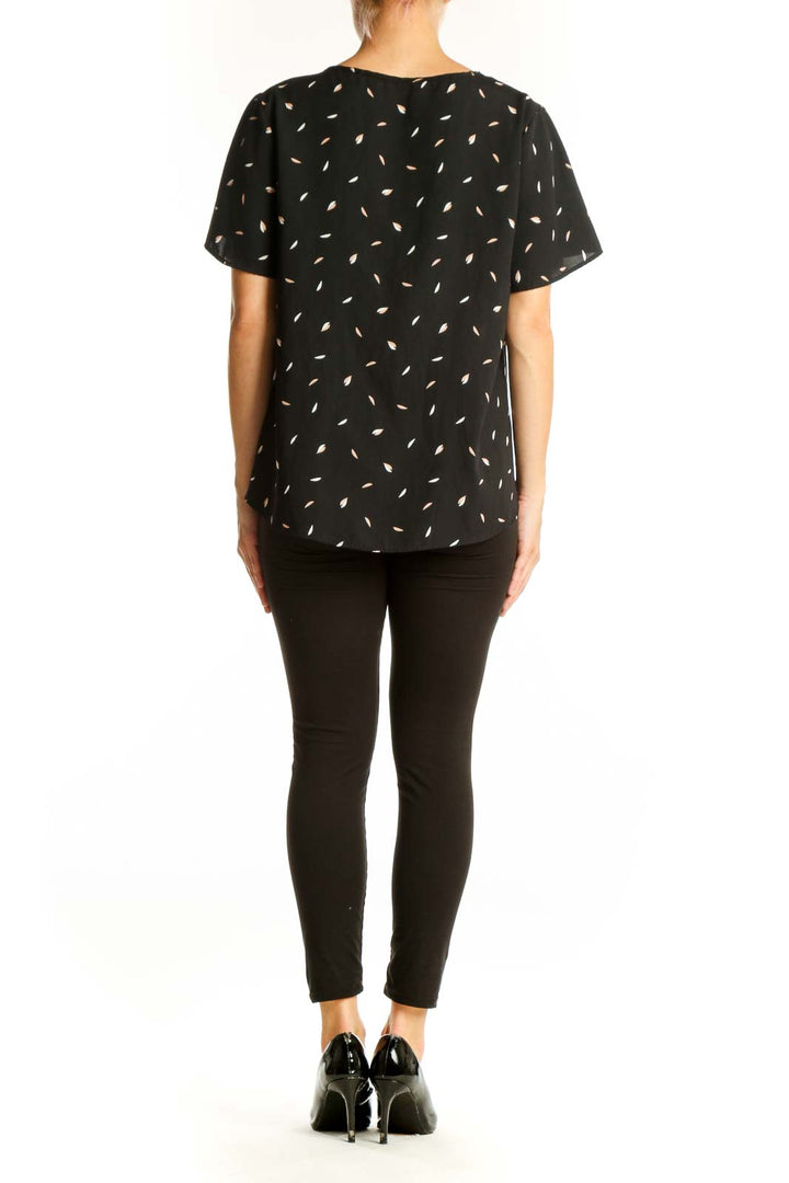 Side view of model wearing West Kei black patterned blouse with dark pants