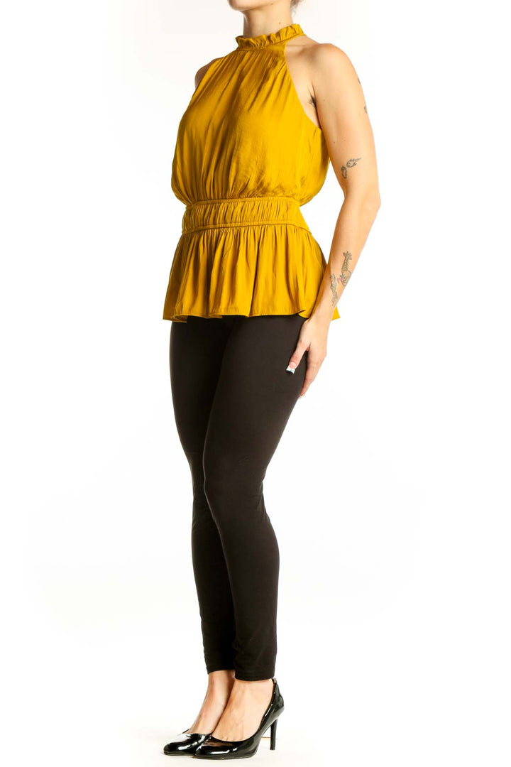 Front view of Nine West mustard sleeveless top with ruffled neckline and peplum waist