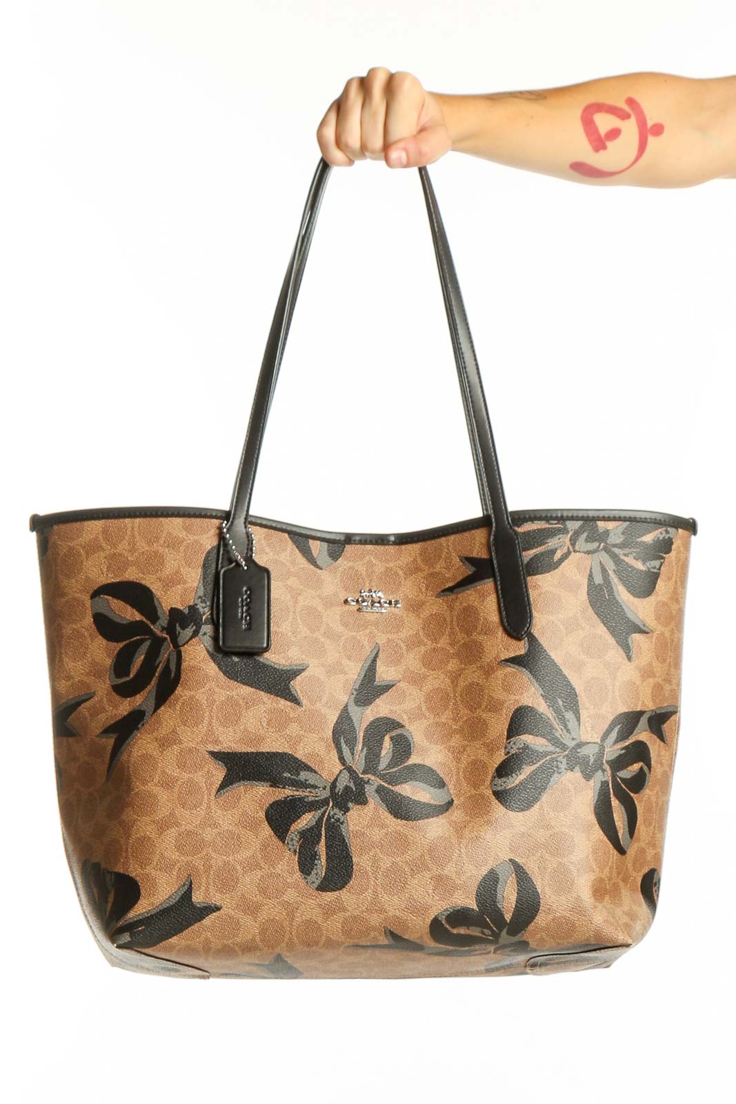 Front view of Coach tan tote bag with black floral print