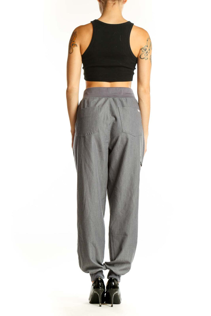 Side view of woman wearing gray FIGS jogger pants with black crop top