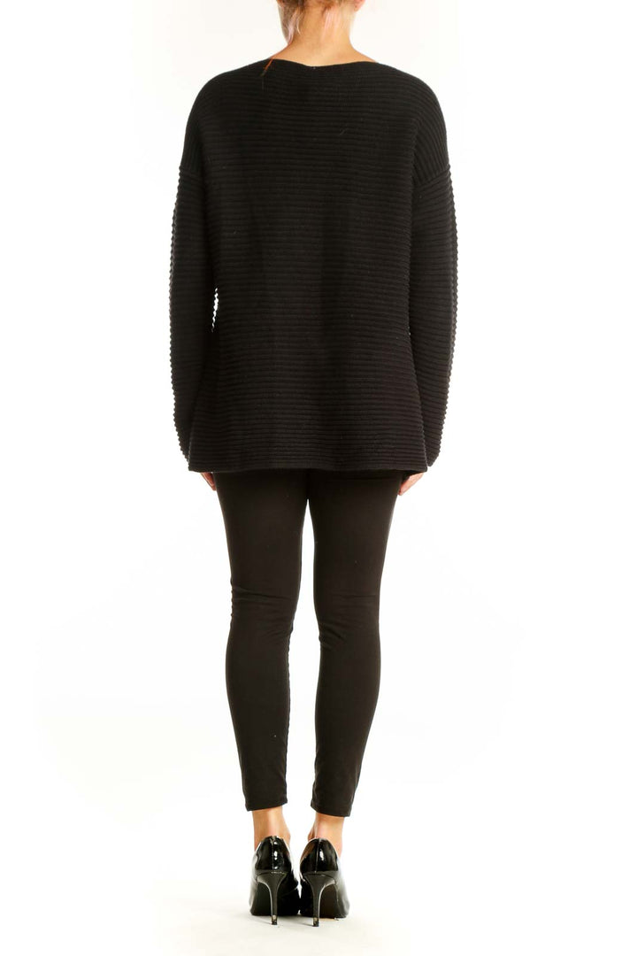 Side view of model wearing Vince Camuto black ribbed knit sweater with leggings