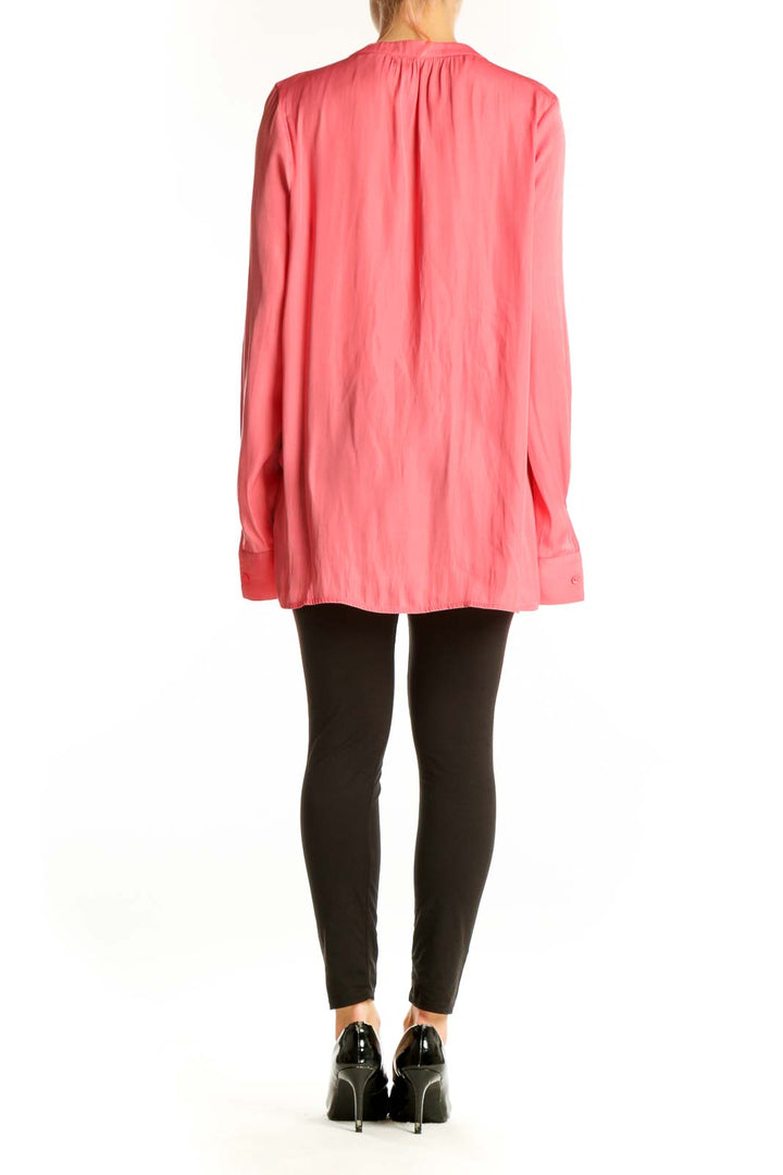 Side view of model wearing pink NYDJ long-sleeve polyester blouse with black pants