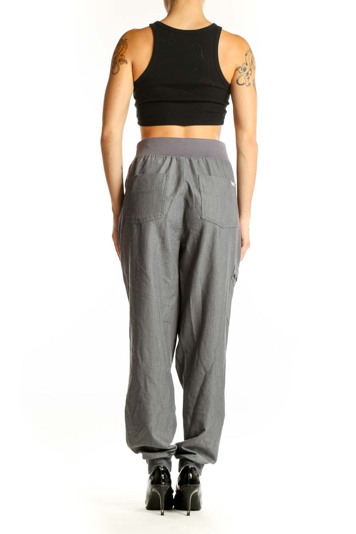 Side view of woman wearing gray FIGS jogger pants with black crop top