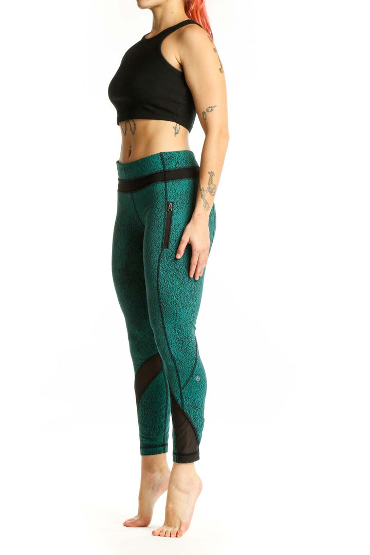 Front view of teal heathered Lululemon crop leggings with black mesh panel inserts and high-waisted design