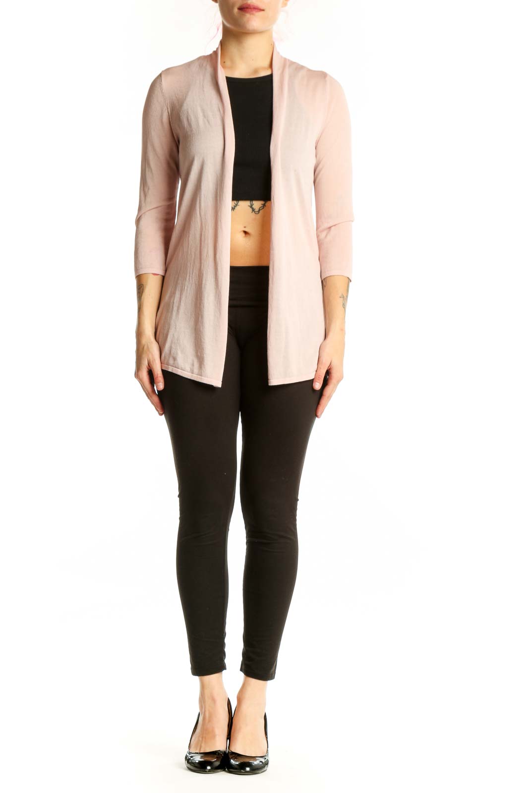 Woman wearing blush pink open front cardigan over black top, styled with black pants