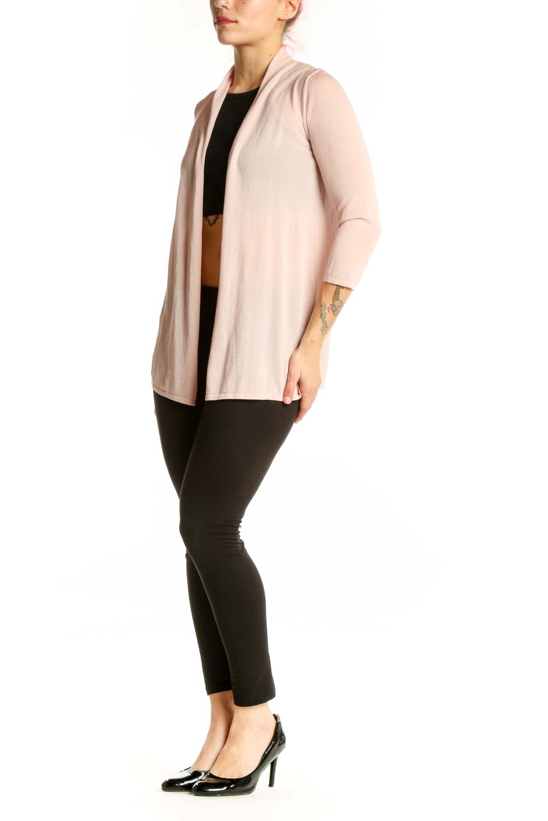 Woman wearing blush pink open front cardigan over black top, styled with black pants
