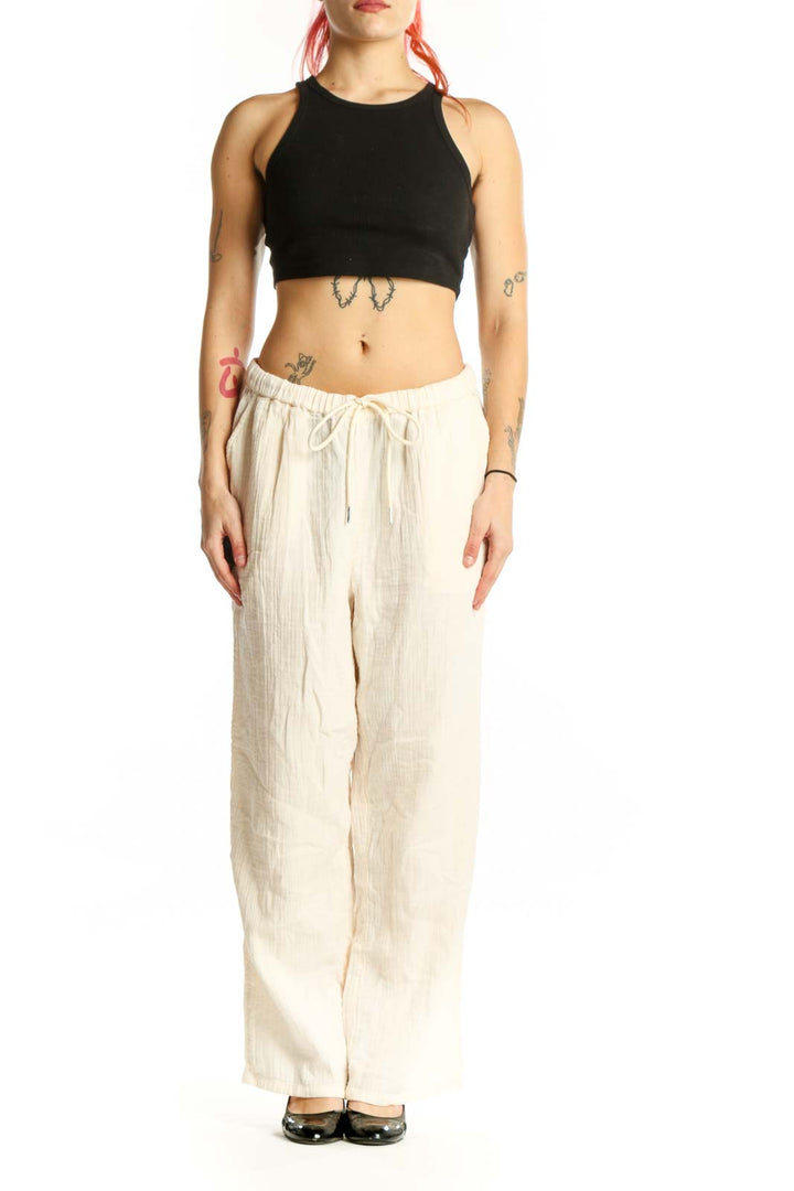 Front view of cream organic cotton drawstring pants with relaxed wide-leg fit and adjustable waist