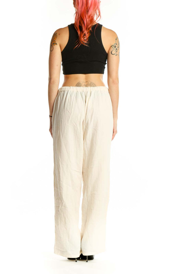 Back view of cream organic cotton drawstring pants showing relaxed silhouette and draping